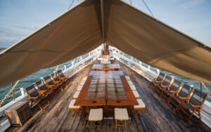 Outdoor dining on the top deck aboard small cruise Katharina sailboat with a large table, chairs, and an awning.
