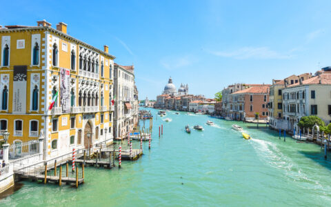A Venice canal of turquoise water flanked by bright gold buildings on a sunny day during the Best of Croatia luxury cruise.