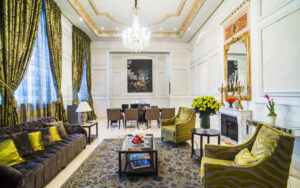 Large couch and oversize chairs near fireplace with large mirror and mural in reception area at Casa Gangotena in Quito, Ecuador