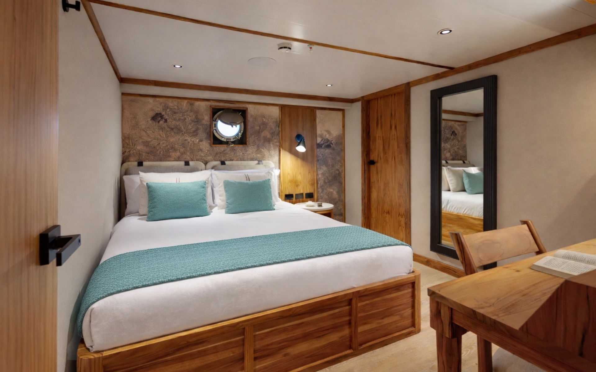 Small ship Evolution's Premium Stateroom with a queen bed, a desk, body-length mirror, porthole window, and light blue accent linens.