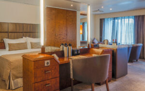 Heritage Suite cabin aboard Heritage Adventurer ship with king bed, free-standing vanity & small living room with view windows.