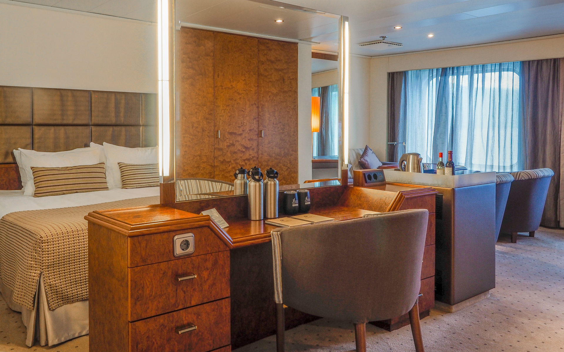 Heritage Suite cabin aboard Heritage Adventurer ship with king bed, free-standing vanity & small living room with view windows.