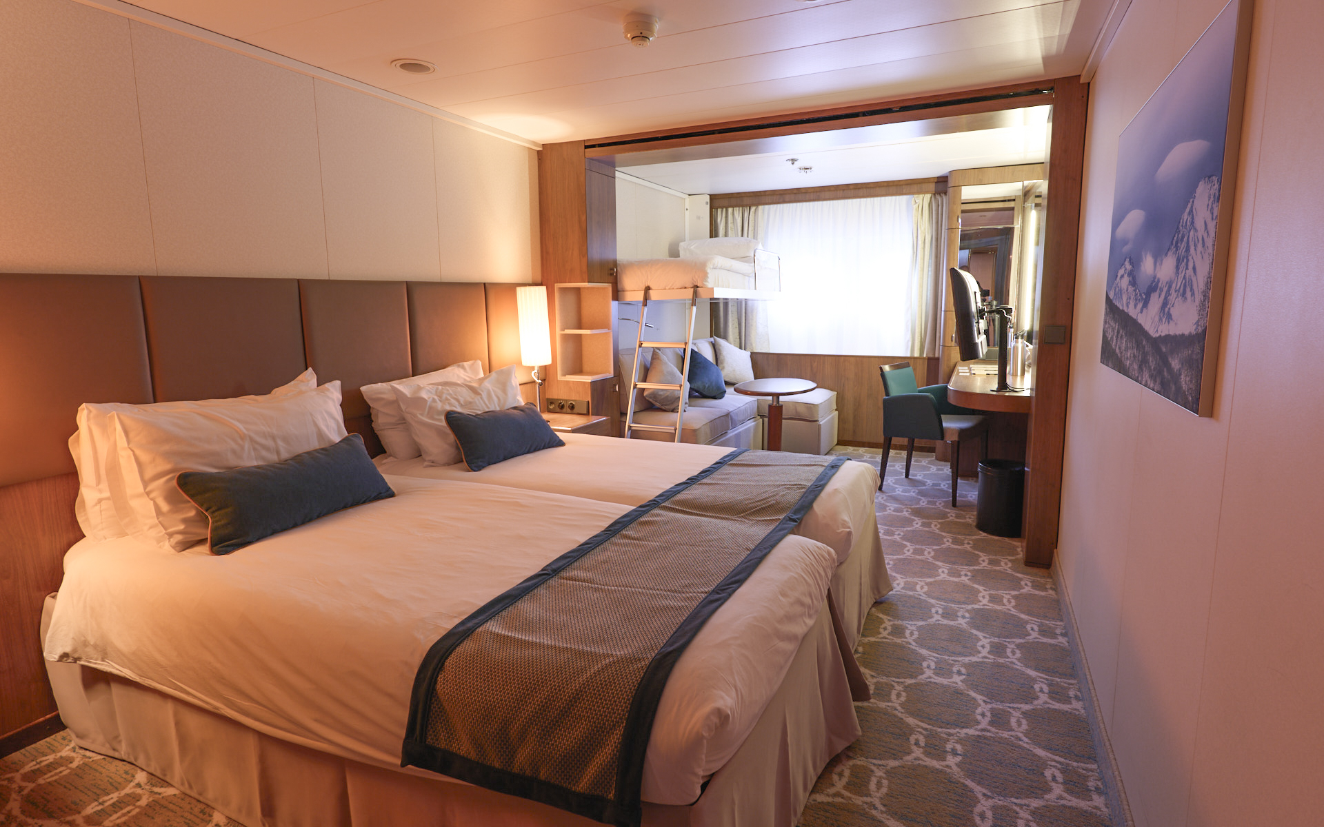 Main Deck Triple cabin on Heritage Adventurer ship. Two twin beds with white linens & brown bed runner. Tan couch & window beside it.