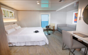 Admiral Cabin aboard the La Pinta small ship with large bed fitted with white linens and day bed, desk & large vertical window