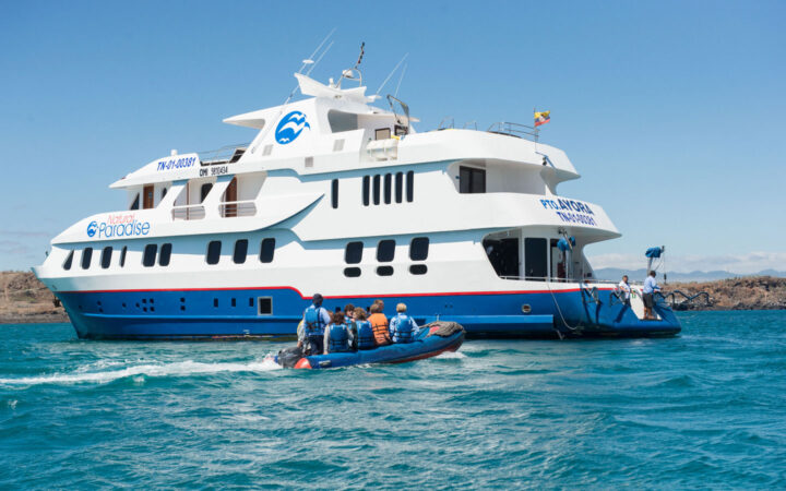 Skiff with guests returning to their small ship Natural Paradise in the blue waters of the Galapagos Islands.