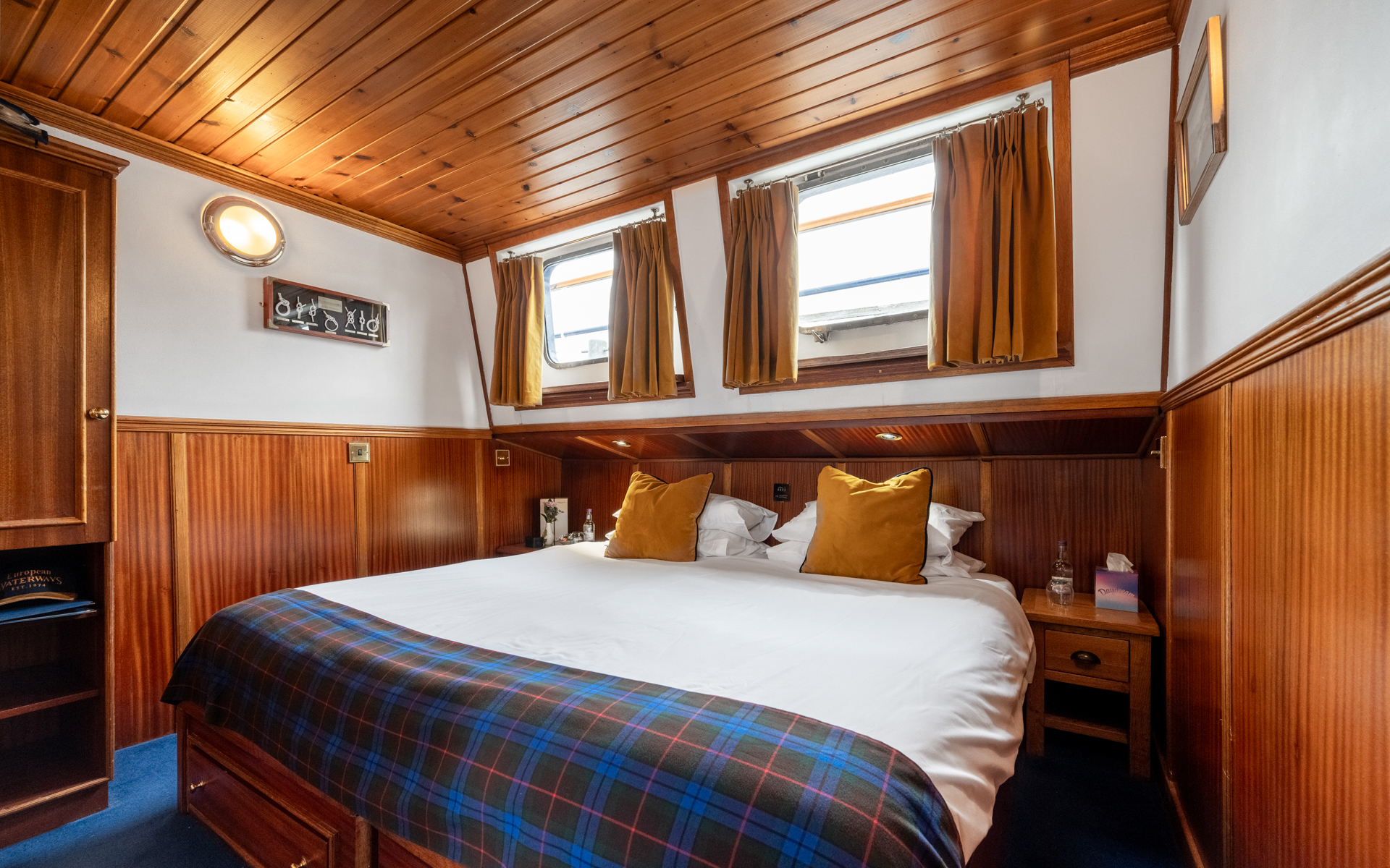 Warmly lit below-deck stateroom with double bed, wooden furniture & 2 windows aboard Scottish Highlander Scotland barge.