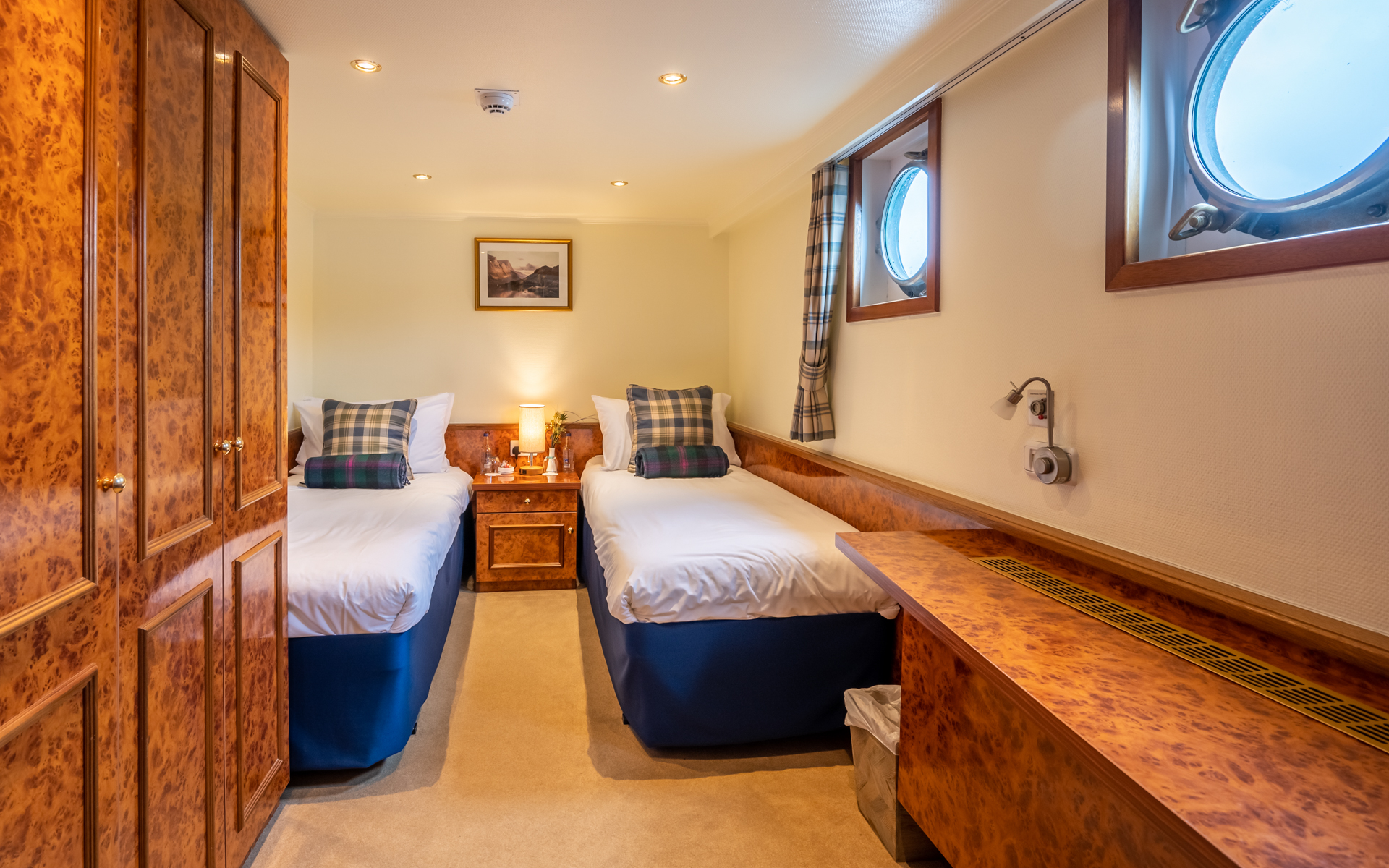 2 twin beds with bedside table between, porthole, & walnut-wood large closet & desk aboard Spirit of Scotland barge.