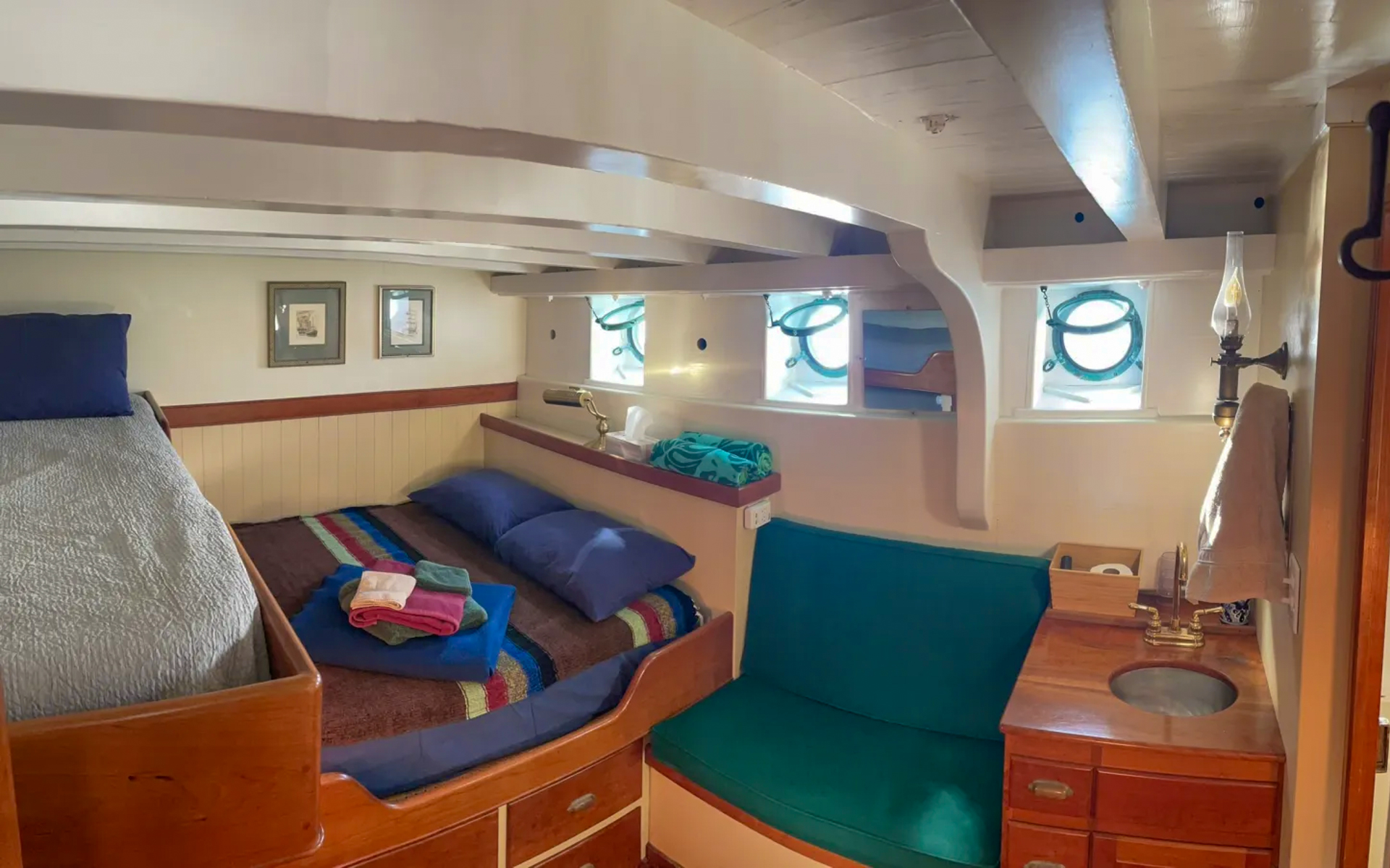 Cabin 3 aboard small ship Westward. Bunk beds with brown, blue, red and green striped comforter. Green chair to right of bed.