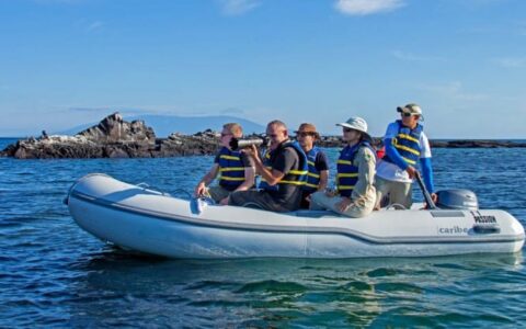 a dinghy full of passengers from the passion luxury cruise heads toward the Galapagos for a day's excursion