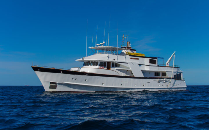 Port side exterior of white small ship Beluga cruising in the Galapagos on a sunny day.