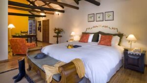 Room interior with bed, bench, armchair, desk and chair at Hacienda Zuleta in Ecuador