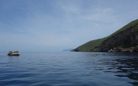 Zodiac cruise with travelers on calm waters offshore from a Galapagos Island