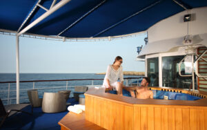 Couple relaxing and soaking in the jacuzzi on Sun Deck under blue awning aboard small ship Isabella II during cruise in the Galapagos.