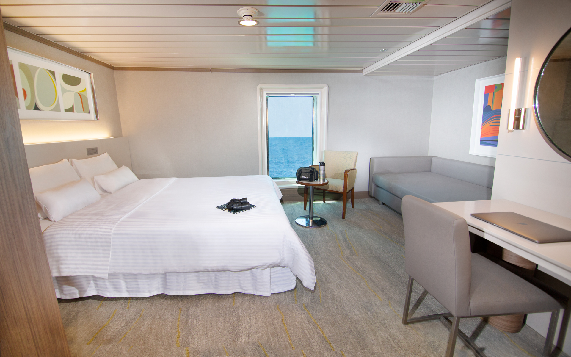 Luxury Plus Cabin aboard La Pinta small ship with large bed fitted with white linens and day bed, desk & large vertical window
