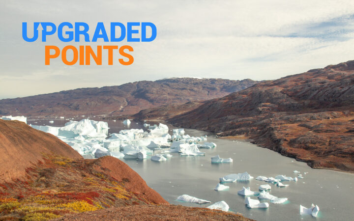 Mountains frame a body of water sprinkled with icebergs in a sound in eastern Greenland. Upgraded Points logo in top left corner.