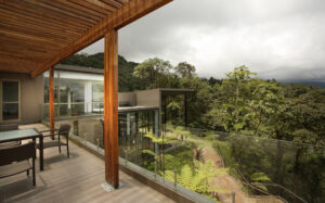 Tables and chairs on a patio overlooking a dense green forest during a cloudy day at the Mashpi eco Lodge, near Quito, Ecuador
