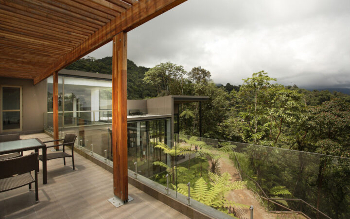 Tables and chairs on a patio overlooking a dense green forest during a cloudy day at the Mashpi eco Lodge, near Quito, Ecuador