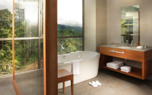 Spacious Yaku Suite bathroom with a full tub, vanity and large windows overlooking the jungle at the Mashpi Lodge in Ecuador