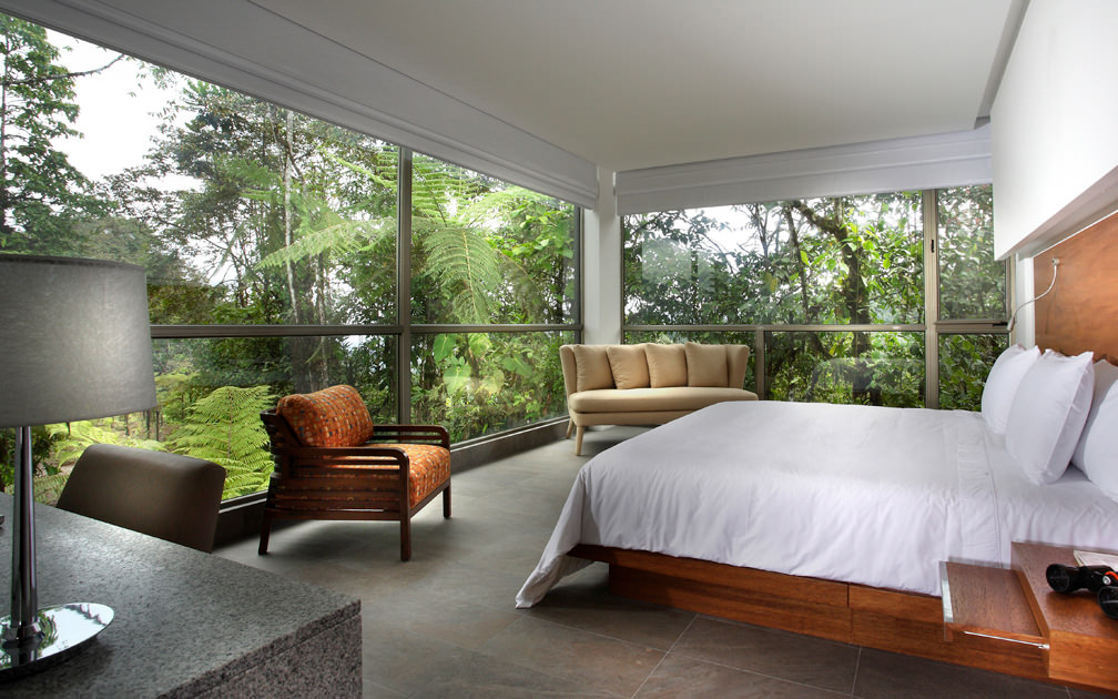 The Yaku King Suite with large bed, fresh white linens and massive windows providing a panoramic view of the jungle at Mashpi Lodge