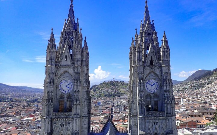 two clock towers of a church with the city behind them on a sunny day on the quito and guayaquil galapagos land tour