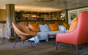 Bar aboard small ship Discoverer: Polar Latitudes with red chair, grey couch and leather chair next to bar.