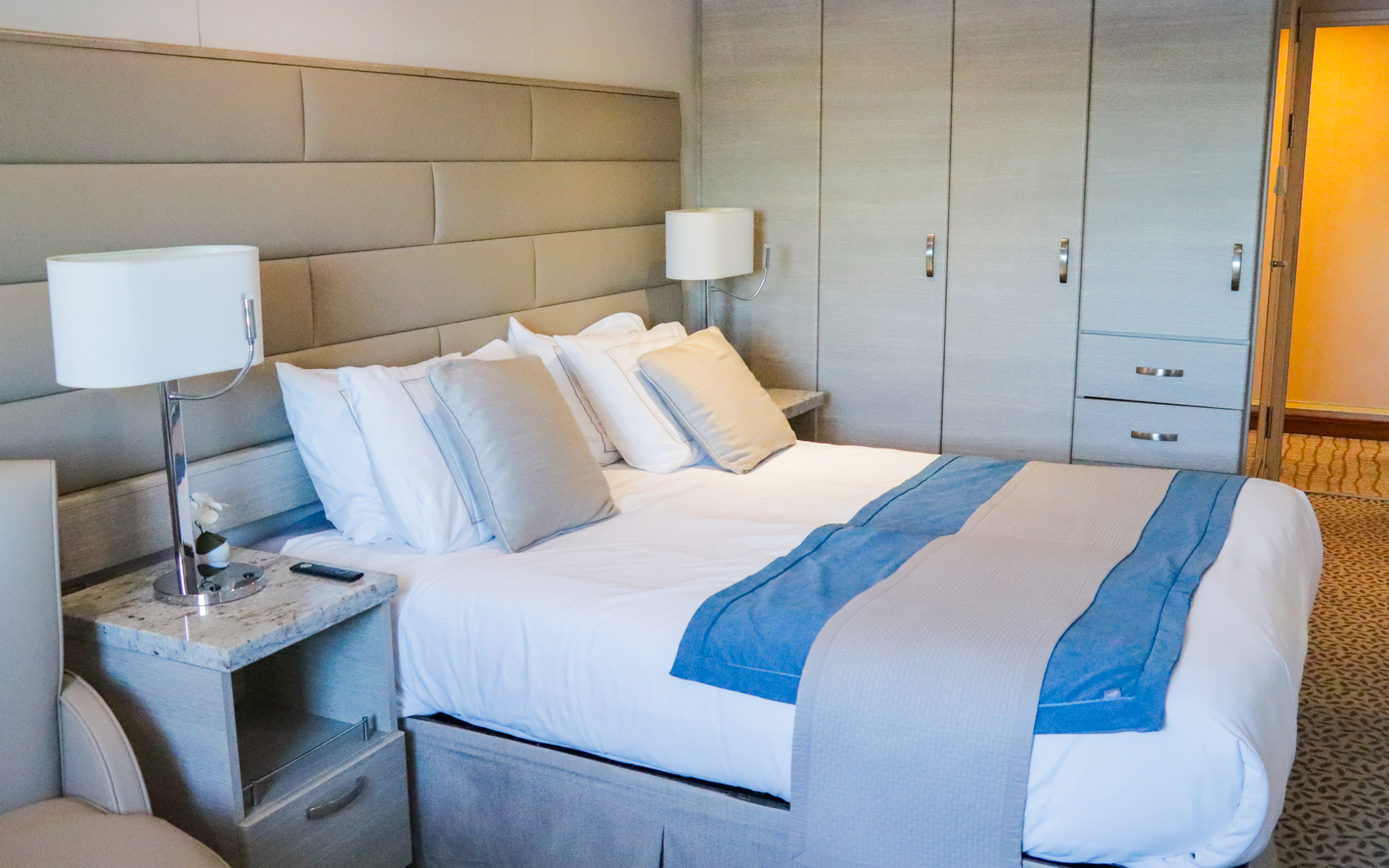 Vista Stateroom aboard Discoverer: Polar Latitudes with large viewing window, vanity, stool, chairs & small table next to a bed fitted in white and tan linens.