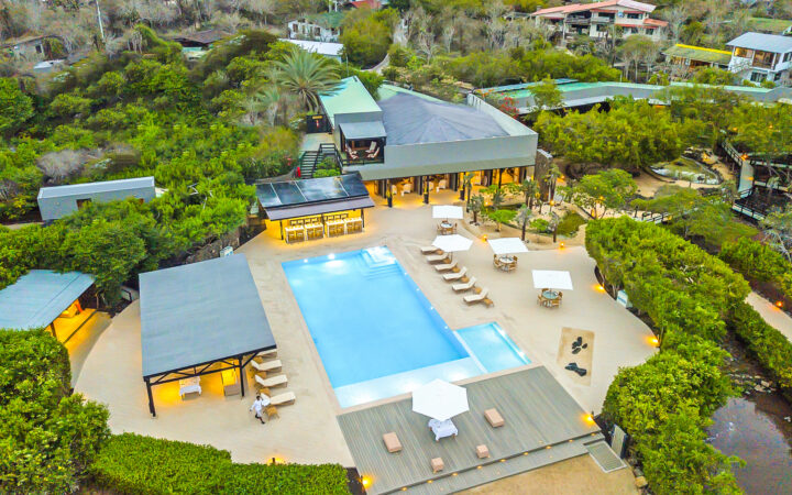 Aerial view of Finch Bay Galapagos hotel with pool, expansive decks and walkways, green gardens & interconnected buildings.