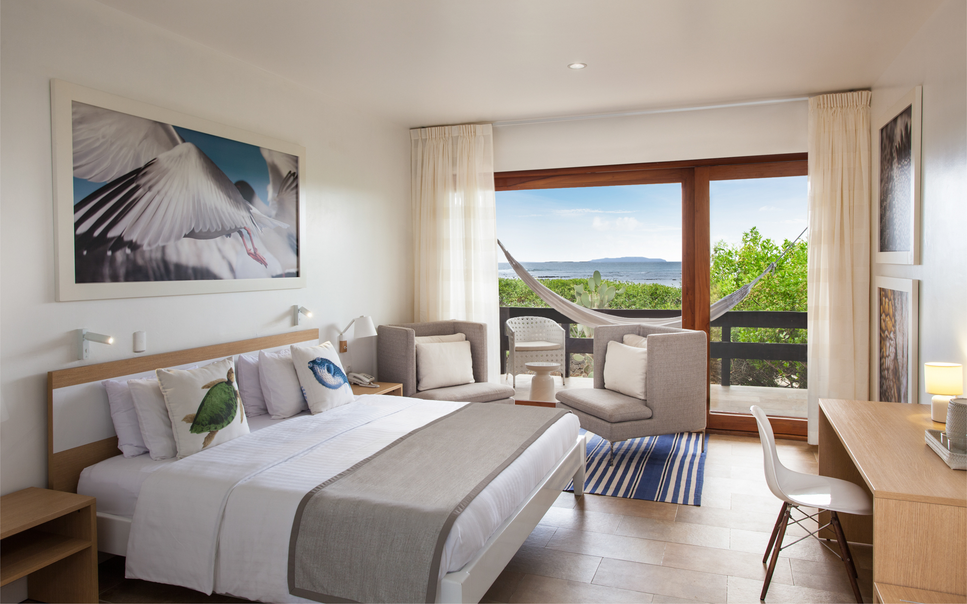 King bed, writing desk, comfortable chairs and hammock with ocean view in suite at Finch Bay Eco Hotel in the Galapagos Islands