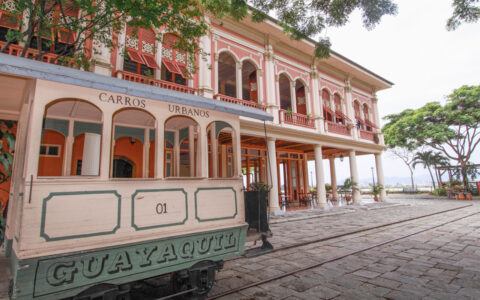 Trolley car in Guayaquil, Ecuador on cobblestone street by colonial pink building, seen on a Galapagos Travel Package tour.