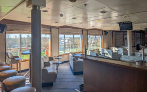 Lecture room aboard small ship Heritage Discoverer with several chairs facing the front of the room & multiple large windows