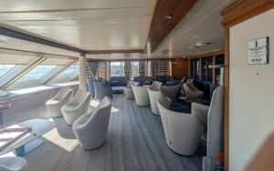 Lounge aboard small ship Heritage Discoverer. Chairs situated throughout the room as natural light pours in from slanted windows