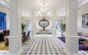 Lobby with couches, armchairs, tables, chairs, decorative columns and paintings inside Hotel del Parque in Guayaquil, Ecuador