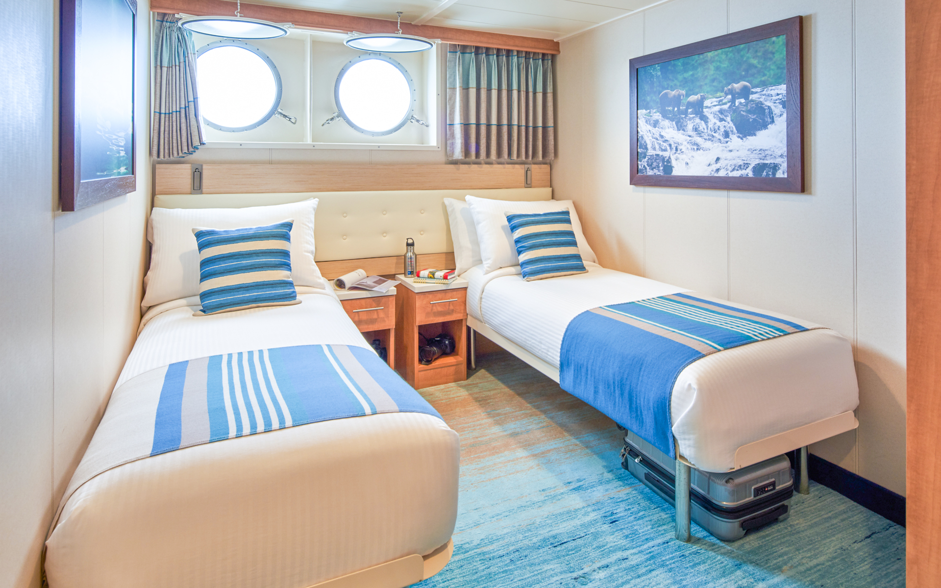 Two twin beds, desk and two portholes in Category 1 cabin aboard National Geographic Quest luxury expedition ship