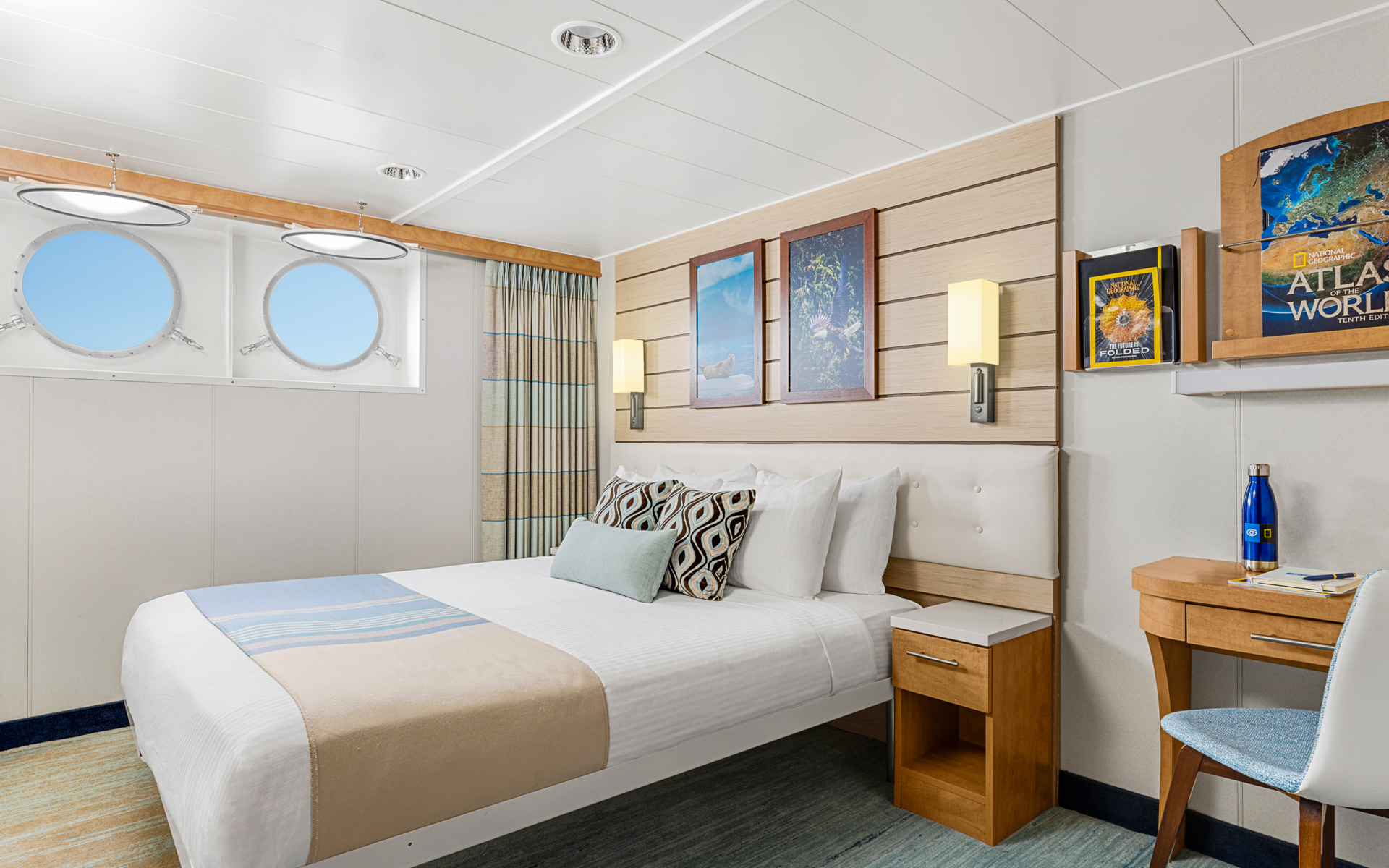 Cat 2 cabin aboard National Geographic Venture expedition ship with queen that can convert to 2 single beds, 2 portholes & nightstand