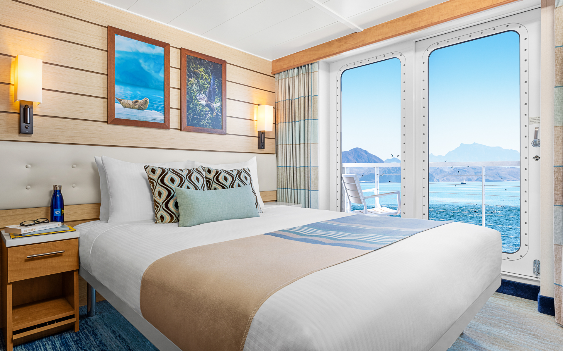 Cat 4 cabin aboard National Geographic Venture fitted with queen that can convert to 2 single beds, door to balcony, and nightstand
