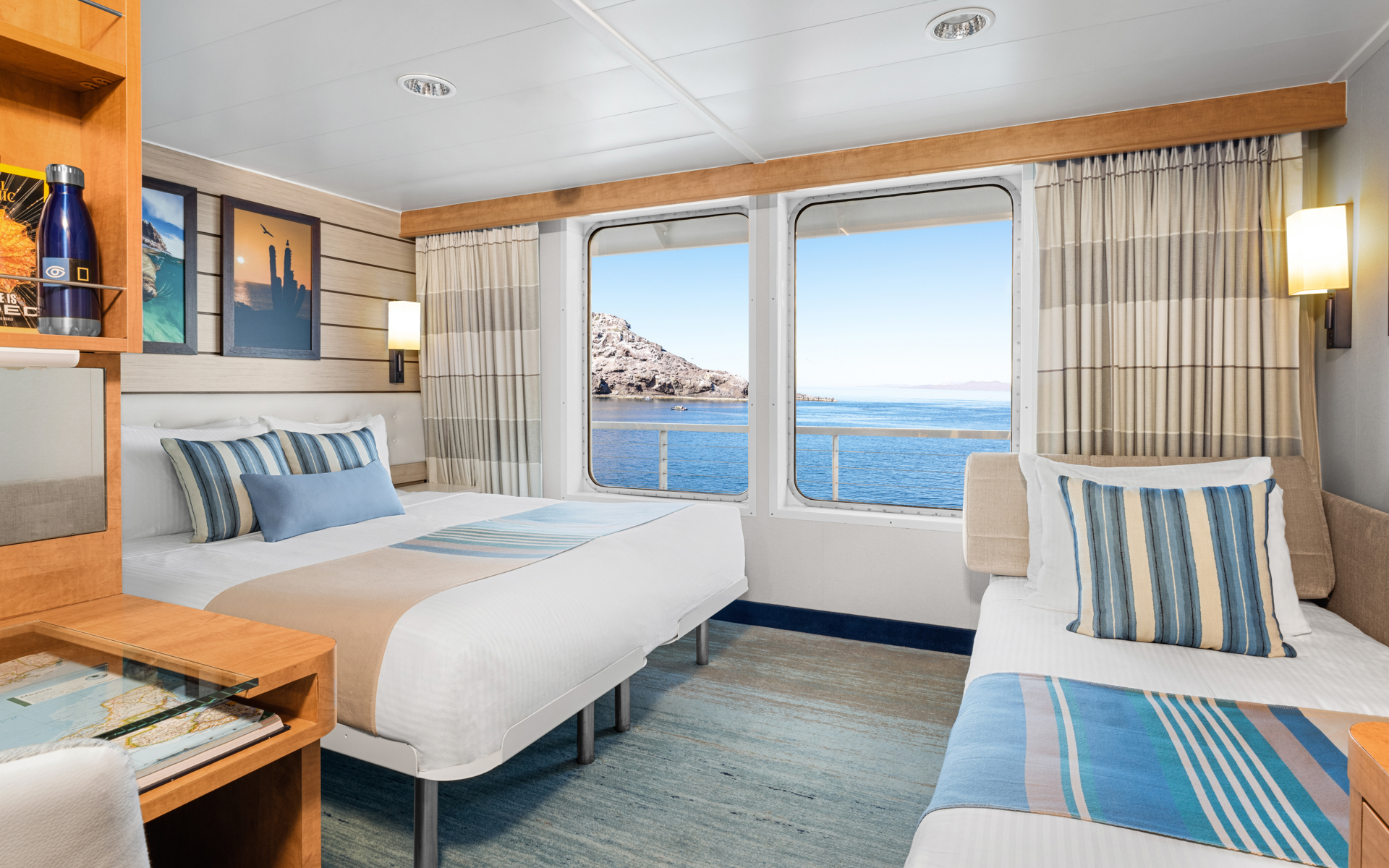 Cat 5 Cabin with large bed, desk, chair convertible sofa bed & large windows aboard National Geographic Venture expedition ship