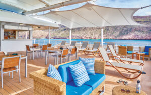 Lounge chairs, couch, arm chairs, tables and patio chairs situated near the bar on Sun Deck of National Geographic Venture ship