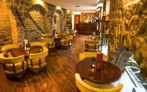 Pub tables placed inside the bar at the Hotel Patio Andaluz in Ecuador. Walls made of stone, giving the bar a wine cellar feel.
