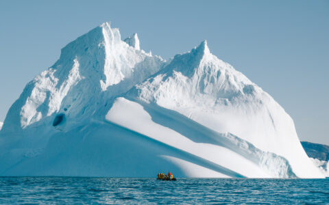 Zodiak next to towering iceberg in Ilulissat Icefjord, a UNESCO World Heritage Site during Southeast to West Greenland cruise
