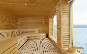 Wood sauna aboard Ultramarine expedition ship, with long wraparound bench, water bucket & a large window revealing polar seascapes.