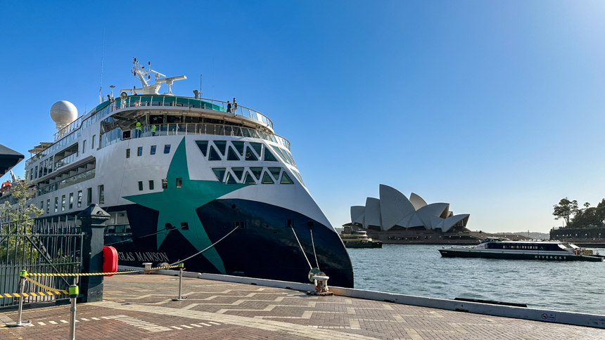 Douglas Mawson tied up in Sydney harbor with bright green star on the side of the ship with the Sydney Oprah house off in the distance 