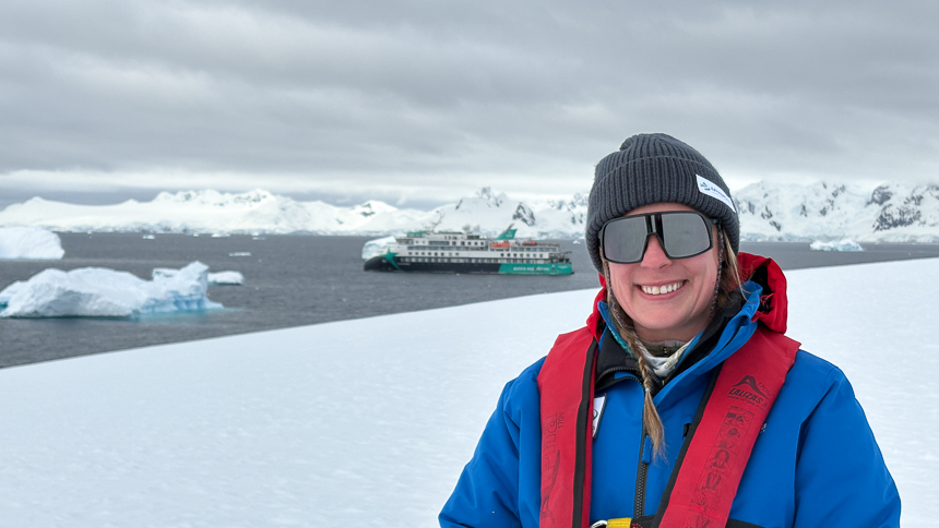 AdventureSmith explorations expert Jenn smiling dressed in winter gear standing  on land on a small ship cruise aboard Sylvia earle 