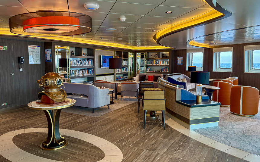 library aboard Sylvia Earle with comfortable seating chairs and couches, picture windows, and ambient lighting, and an old scuba mask 