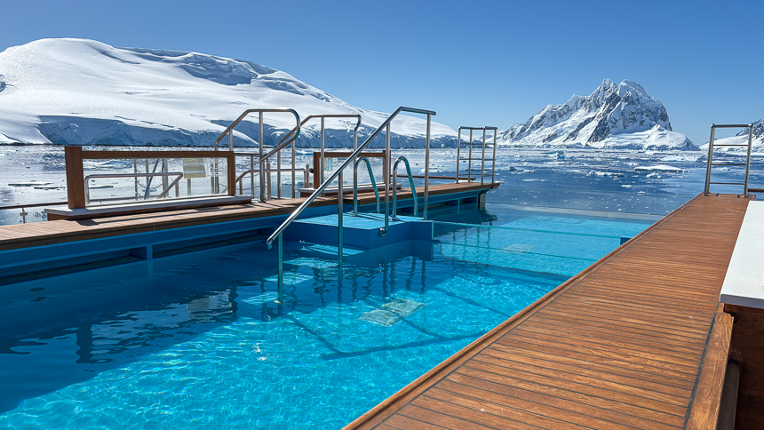 pool aboard small ship cruise with hot tub off in the distance, snowy mountains off in the distance 
