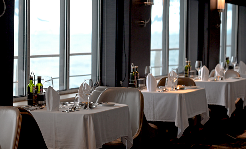 Dining room aboard Magellan explorer with white tables, large picture windows and seating for two