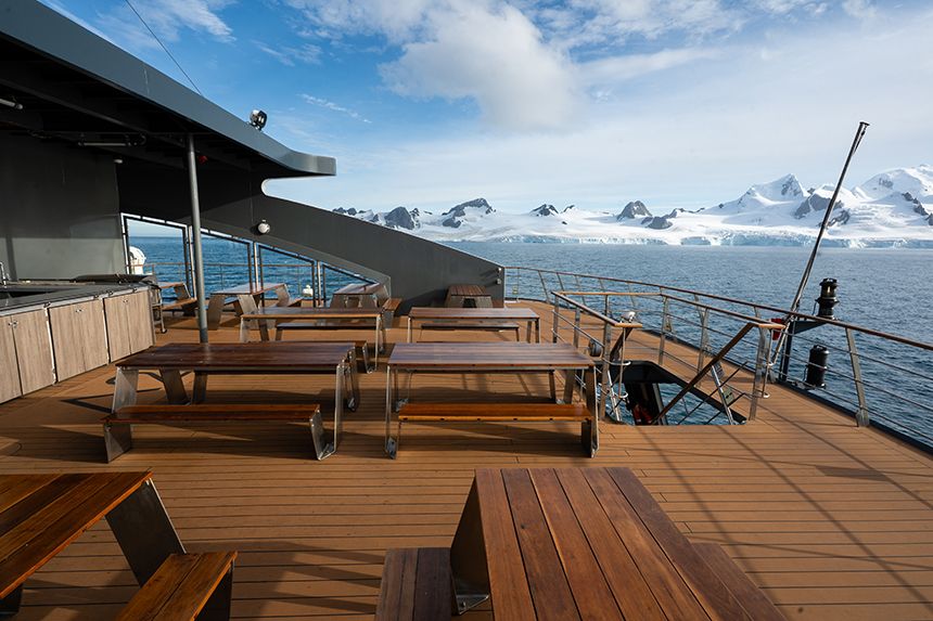 Outdoor seating aboard Magellan explorer on a nice sunny day with mountains off in the distance in Antarctica