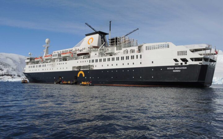 Ocean Endeavor expedition cruise anchored while passengers board several zodiacs
