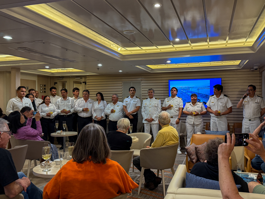 Staff of small ship cruise standing in front of guests, with a glass in hand to cheers with