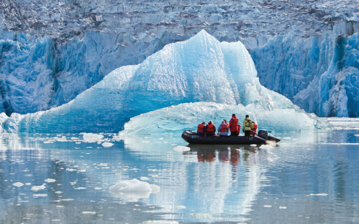 Zodiac dinghy with Treasures of the Inside Passage: Alaska & British Columbia cruise guests motors past a massive piece of glacier ice.
