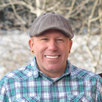 Portrait of Kiel Sprague in a plaid shirt with snowy background and a fence